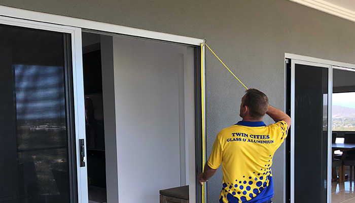 Man measuring door from Twin Cities Glass and Aluminium Townsville